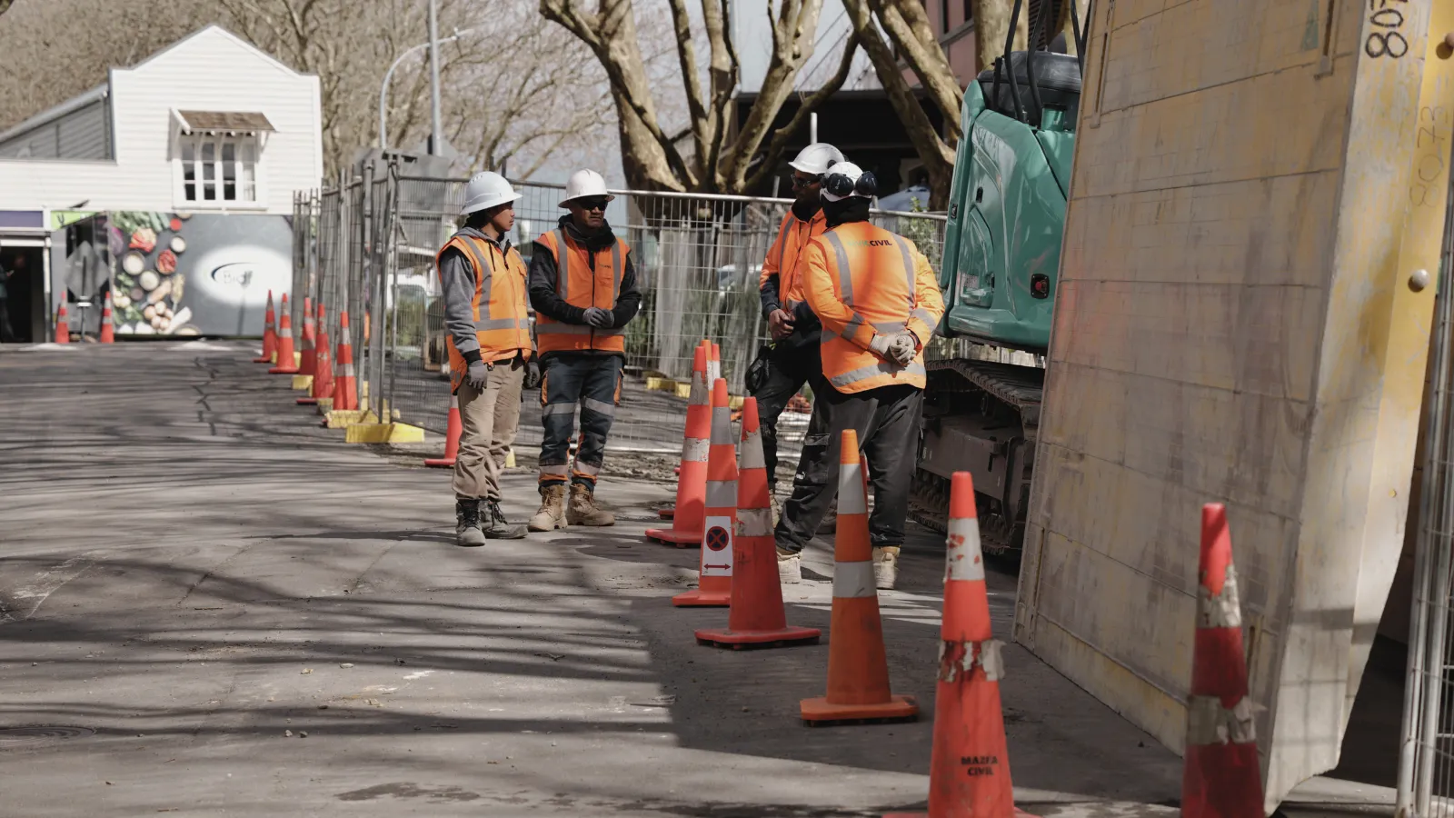 Livic Civil team reviewing work beside an excavator on an Auckland site.