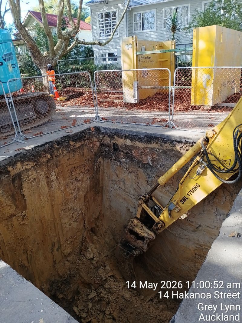 Excavator working in a deep urban excavation.