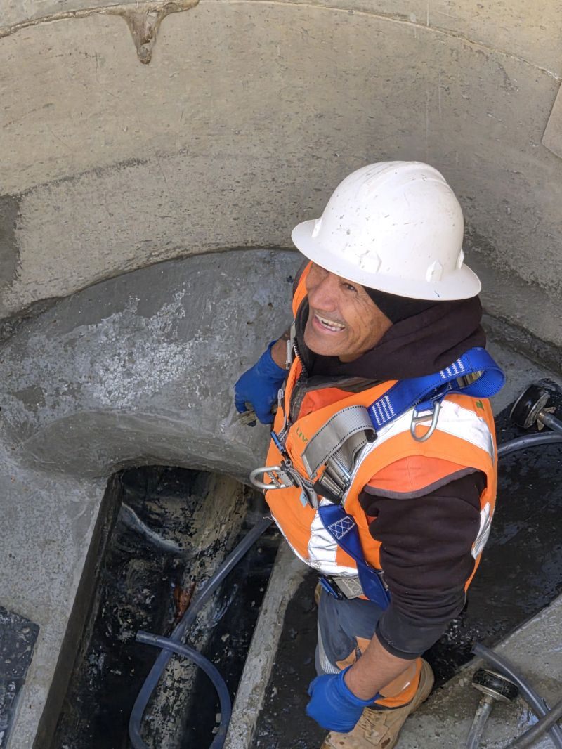 Crew member carrying out an inspection inside a concrete drainage chamber.