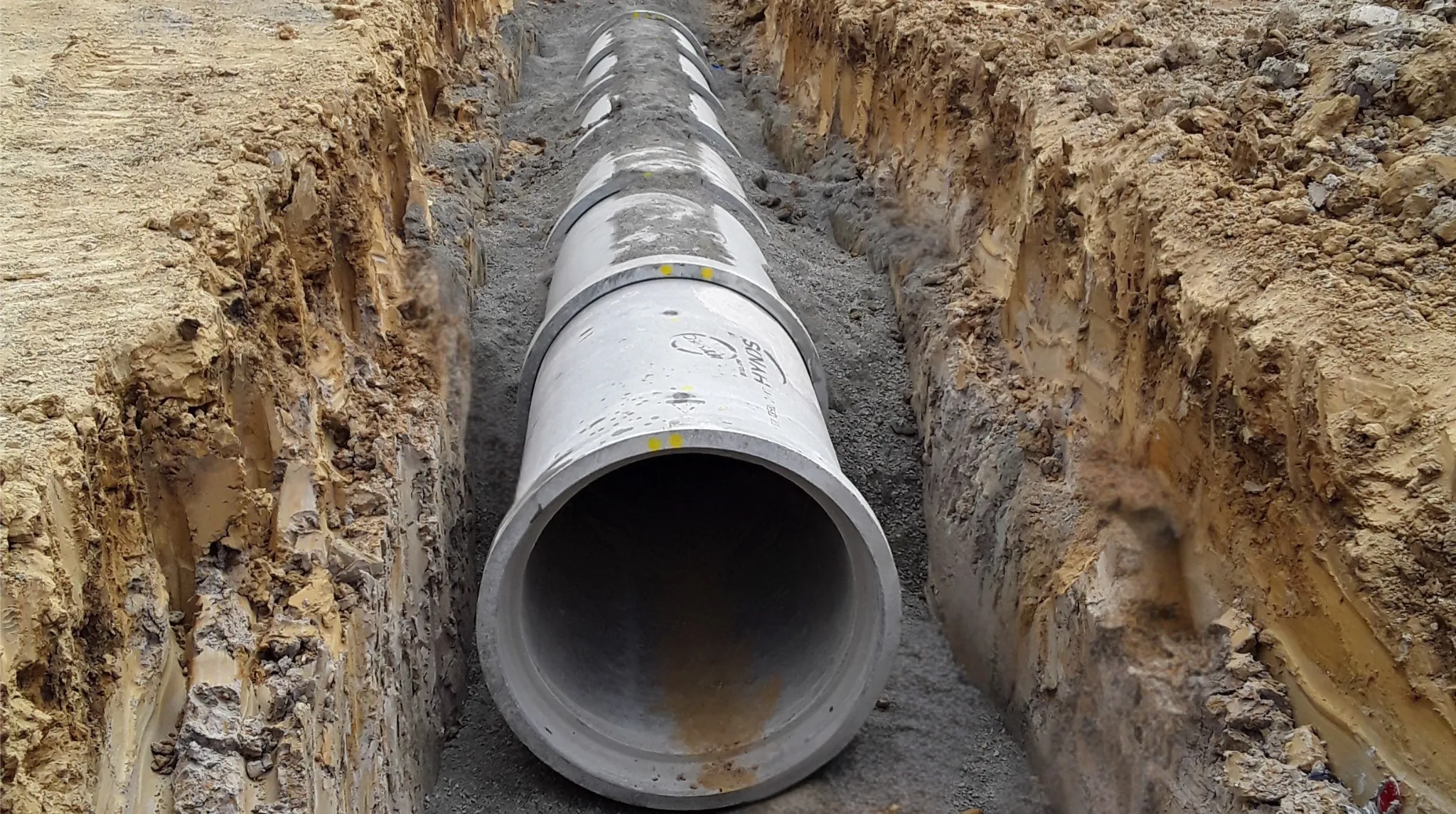 Large concrete stormwater pipe laid in a gravel-bedded trench.