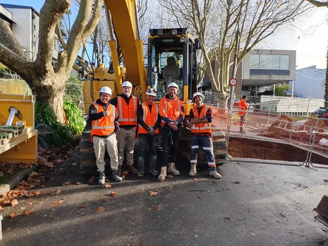 Livic Civil team standing in front of an excavator at a project site.