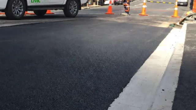 Asphalt surface beside a concrete channel, with temporary cones and a Livic Civil vehicle in the background.