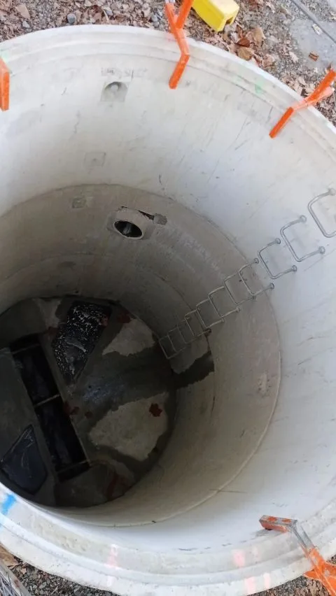 Precast concrete manhole chamber with an installed access ladder.