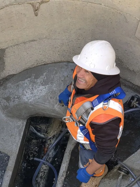 Crew member carrying out an inspection inside a concrete drainage chamber.